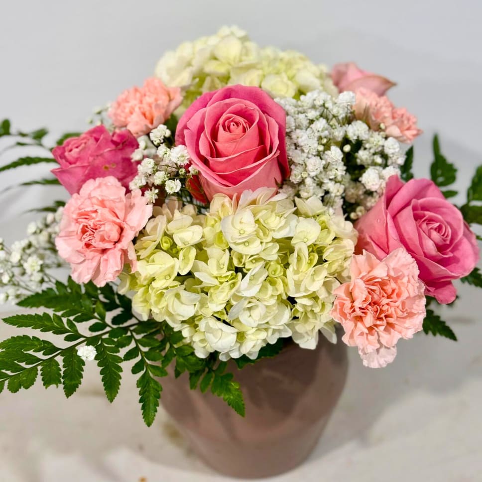 Pink roses and carnations with pale hydrangeas in a vase