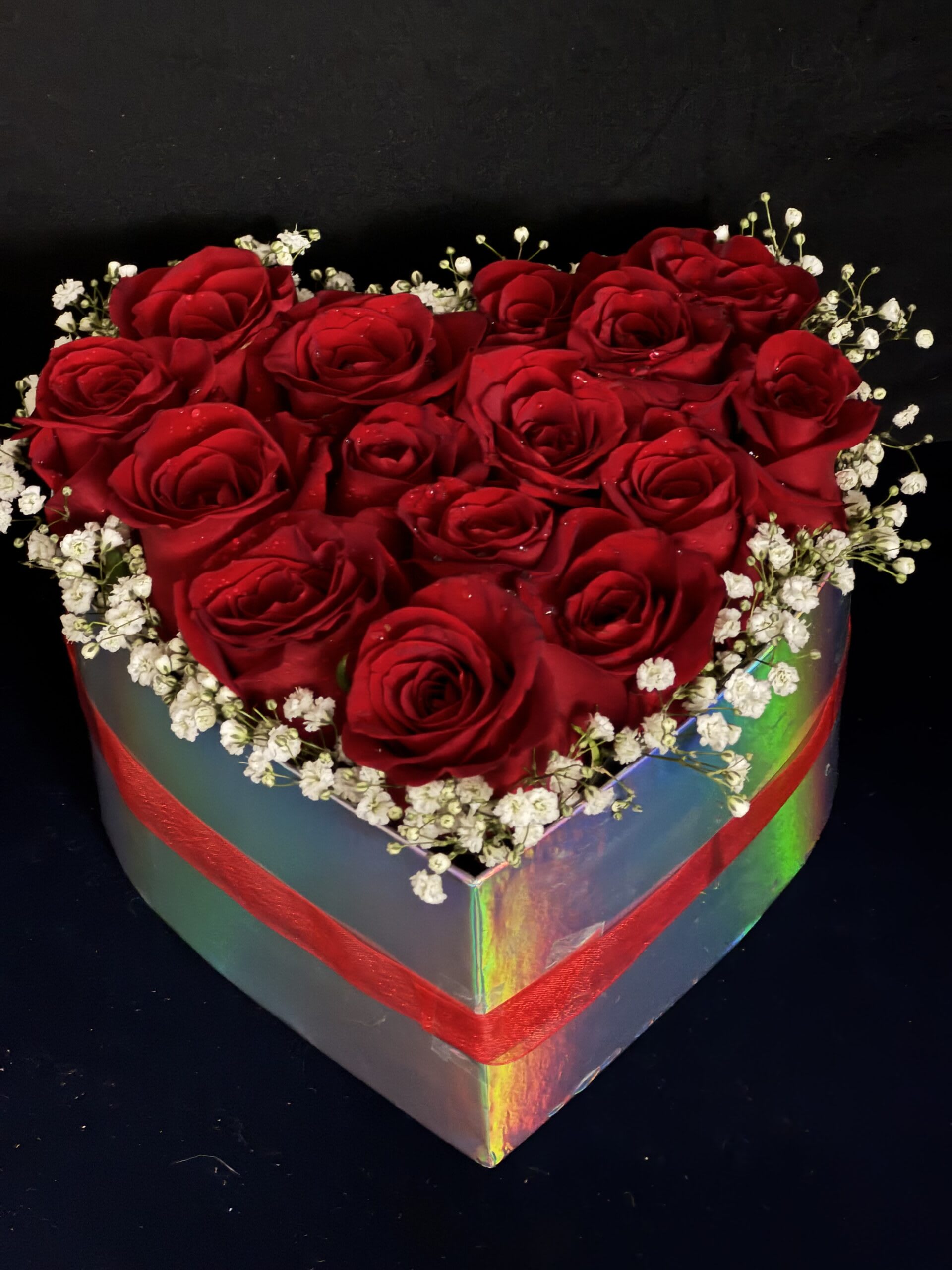 Heart-shaped box filled with red roses and white baby's breath