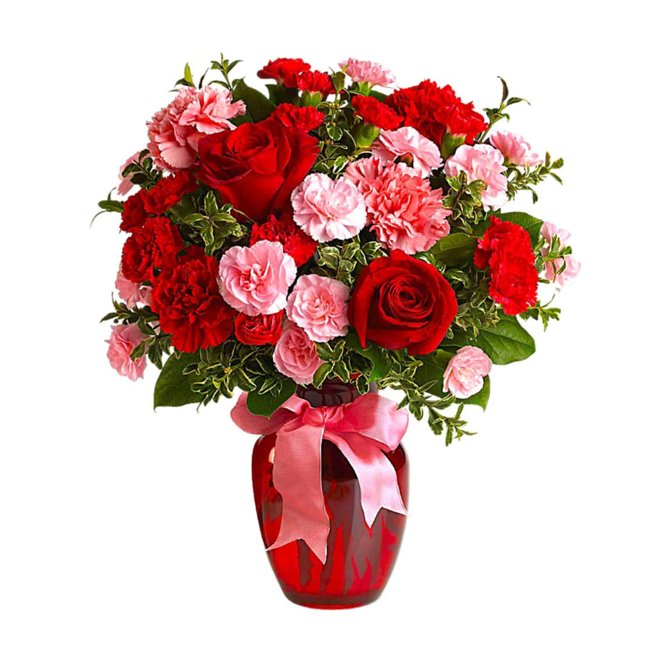 Red and pink flower arrangement in a red vase with a pink ribbon