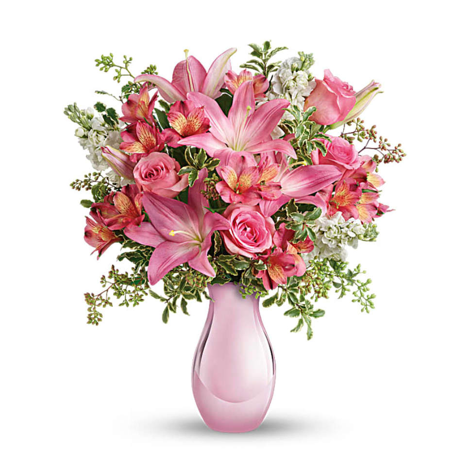 Pink lilies and roses arranged in a pink glass vase