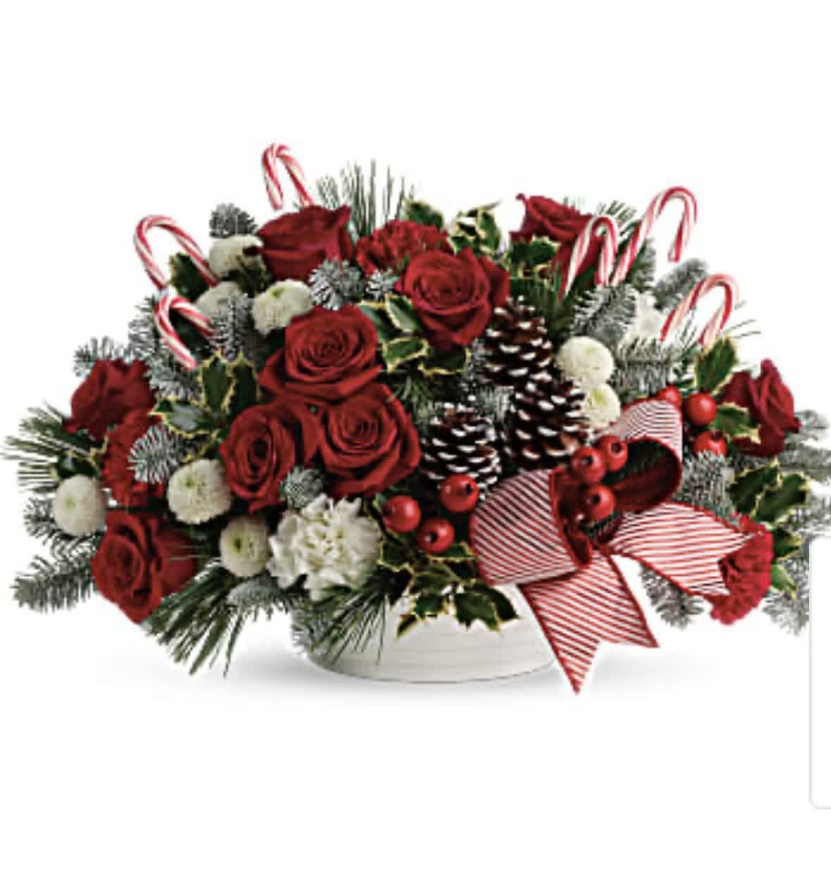 Red roses and holiday greenery in a white bowl with candy canes and ribbon