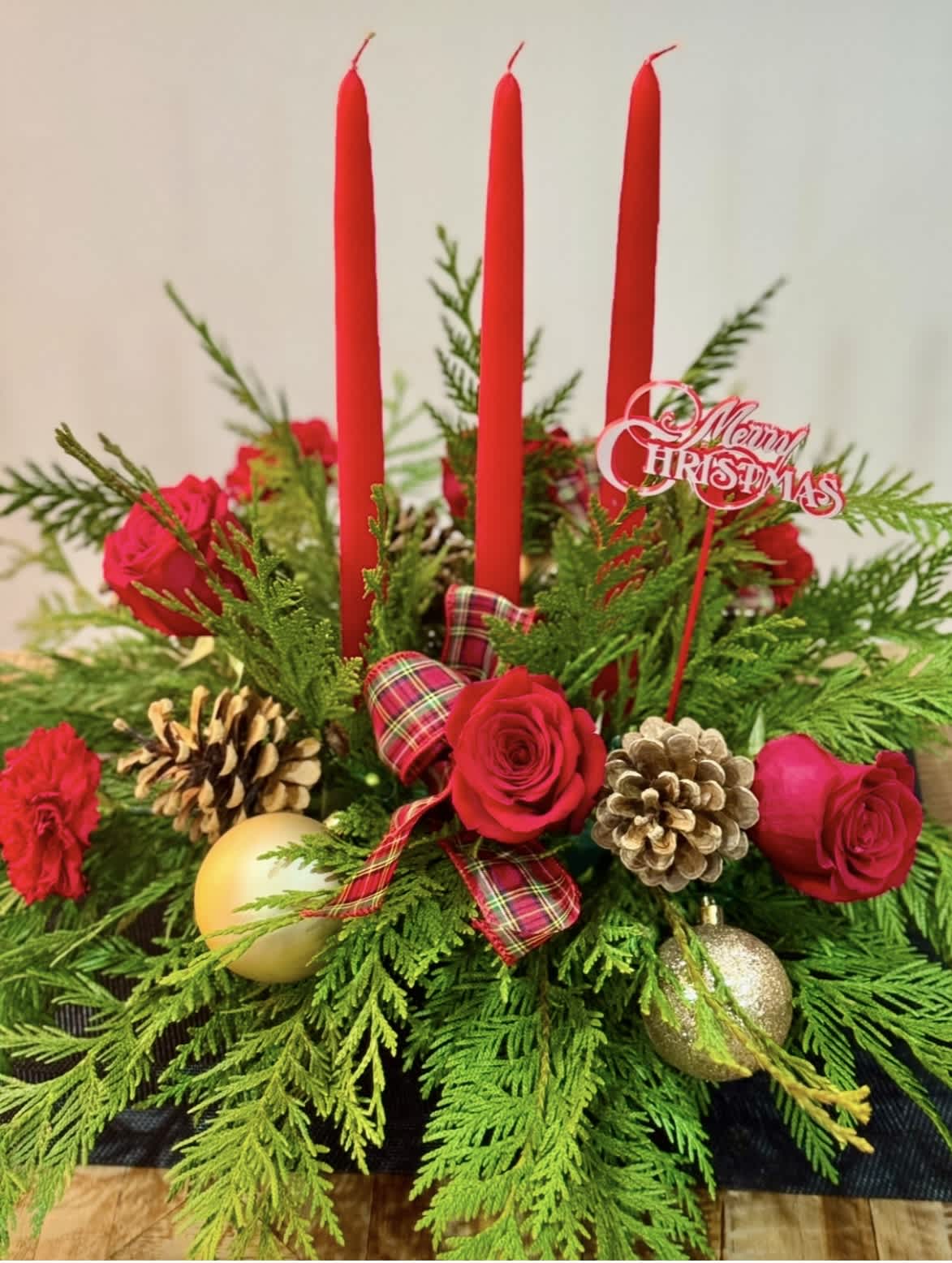 Christmas centerpiece with red roses, candles, and pinecones