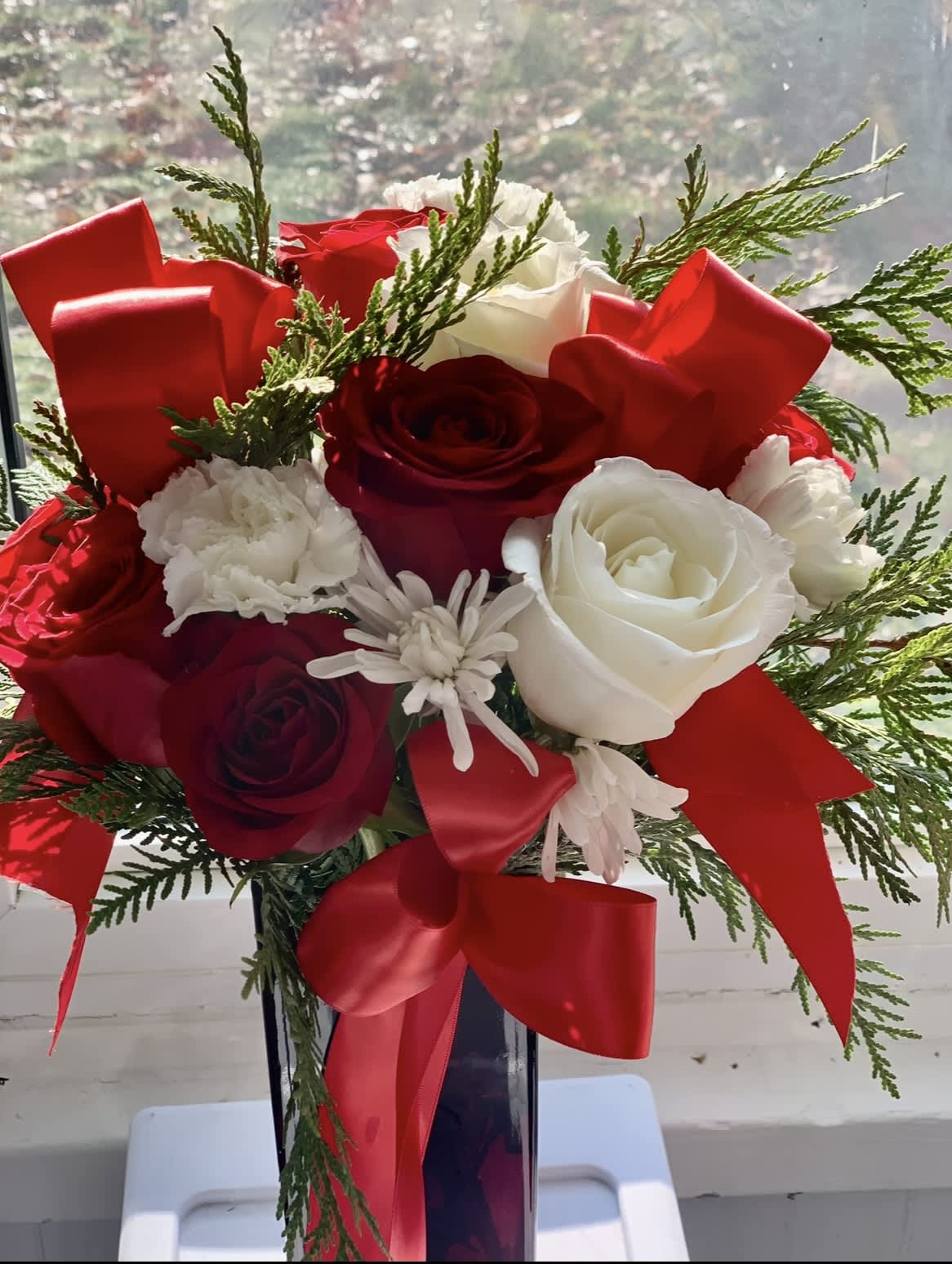Bouquet of red and white roses with red ribbon in a tall vase