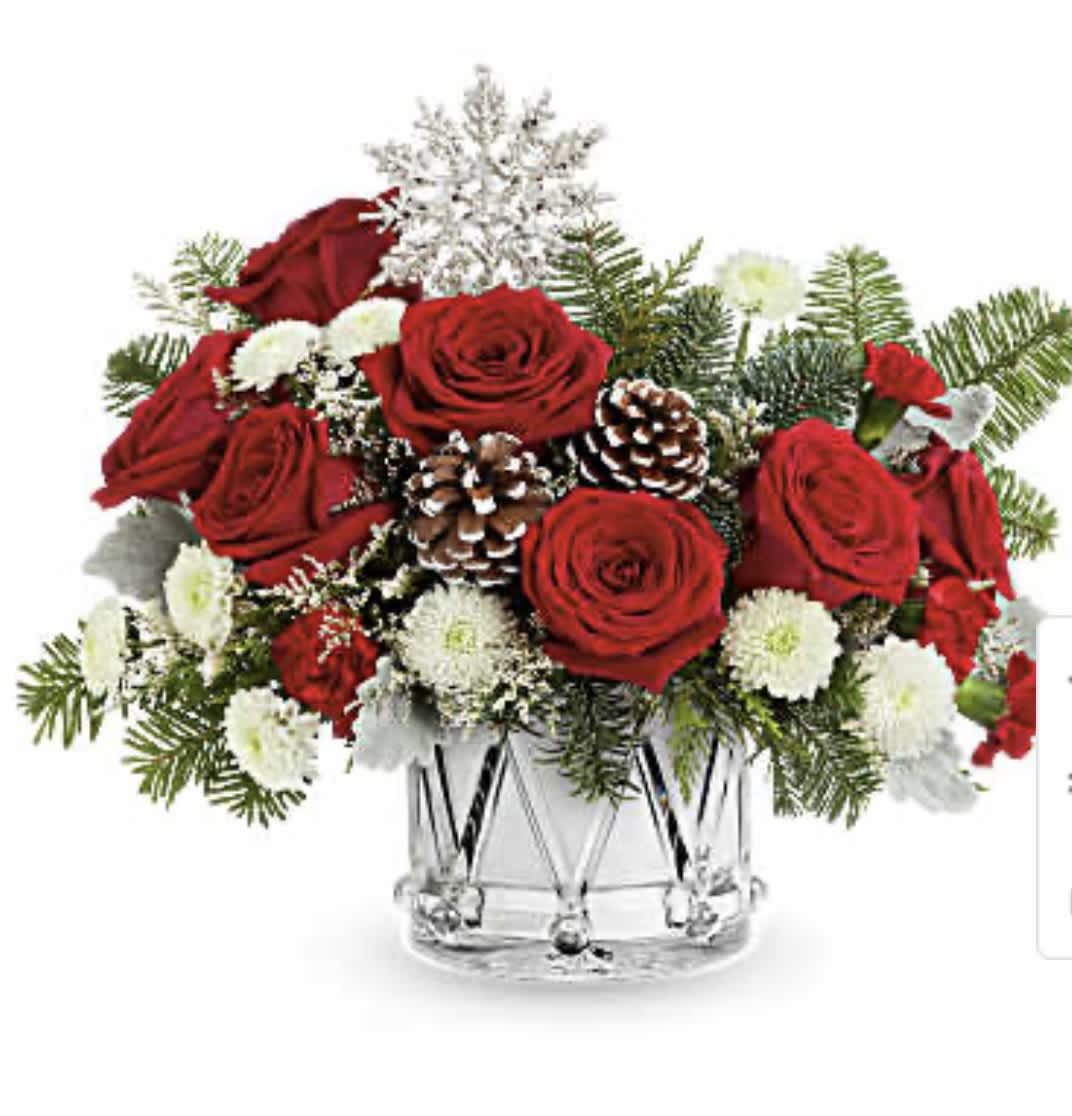 Red roses and white flowers in a clear glass vase with pinecones