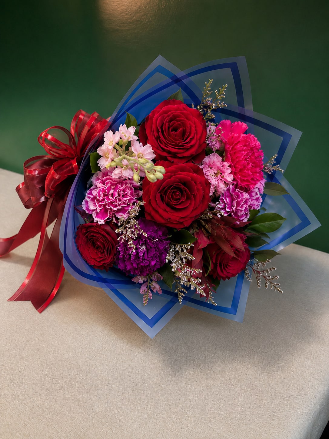 Romance Grab &amp; Go - A romantic hand-tied bouquet featuring premium red roses, vibrant carnations, seasonal blooms, and lush greenery, beautifully wrapped and ready to gift.