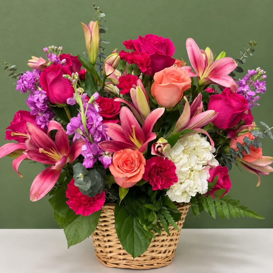 Mixed bouquet in a wicker basket with roses, lilies, carnations, and hydrangea
