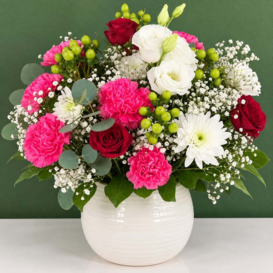 Mixed bouquet of roses, carnations, and white daisies in a white vase