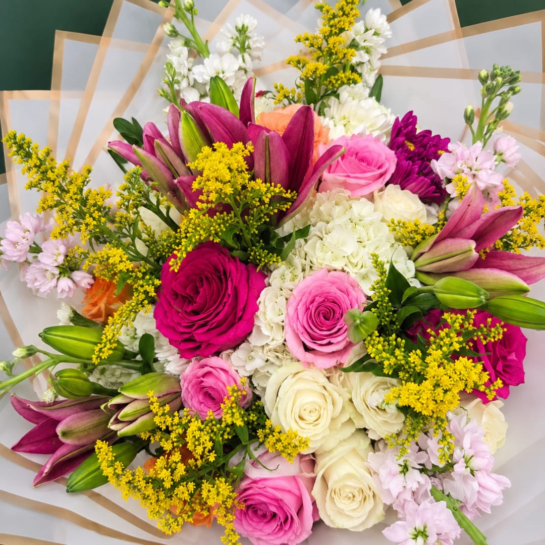 Mixed bouquet of pink, white, and purple flowers wrapped in white paper