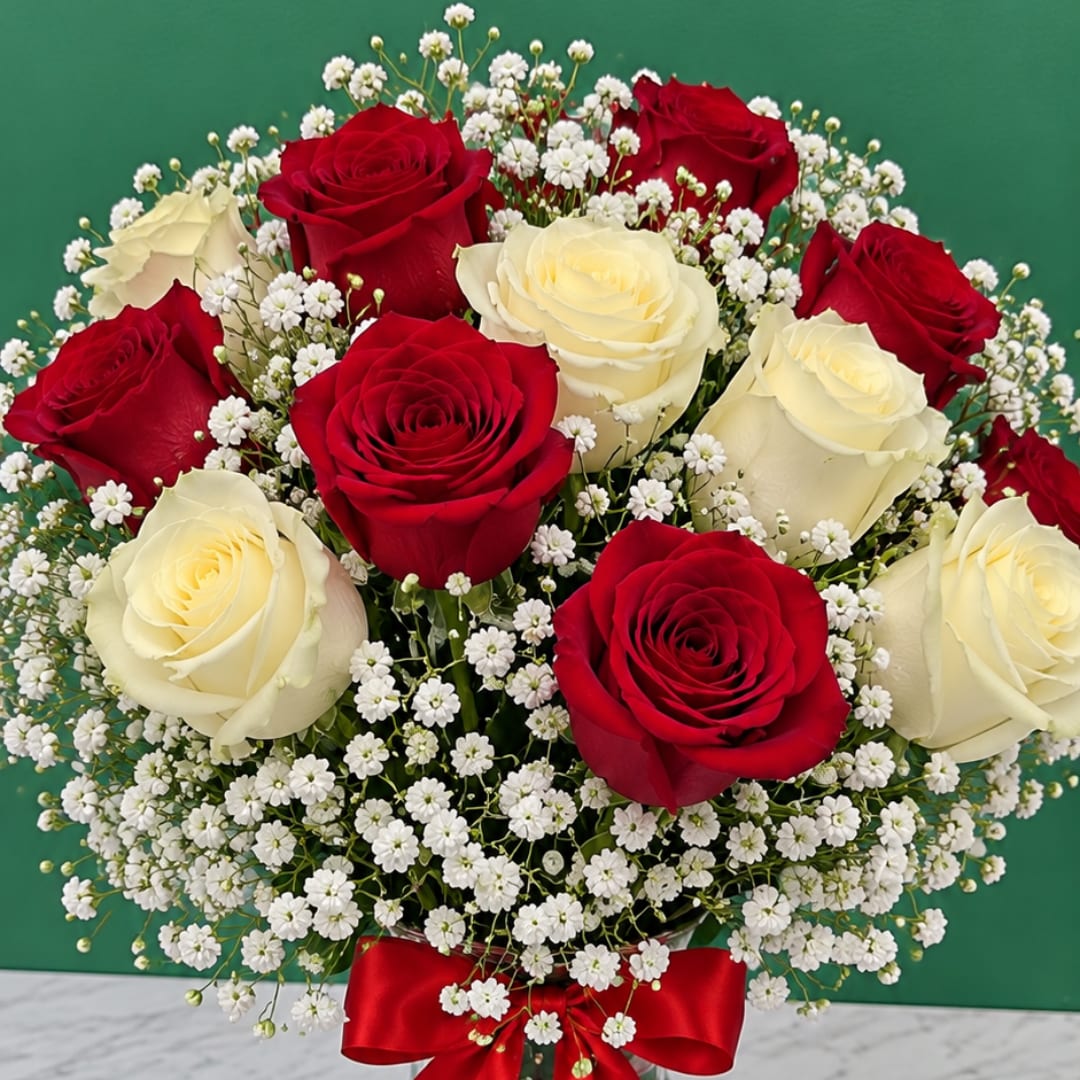 Red and white roses with baby's breath in a bouquet tied with a red ribbon