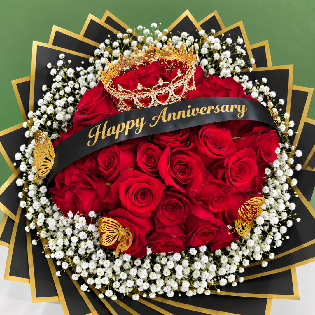 Red roses with baby's breath and a gold crown, wrapped with a Happy Anniversary ribbon