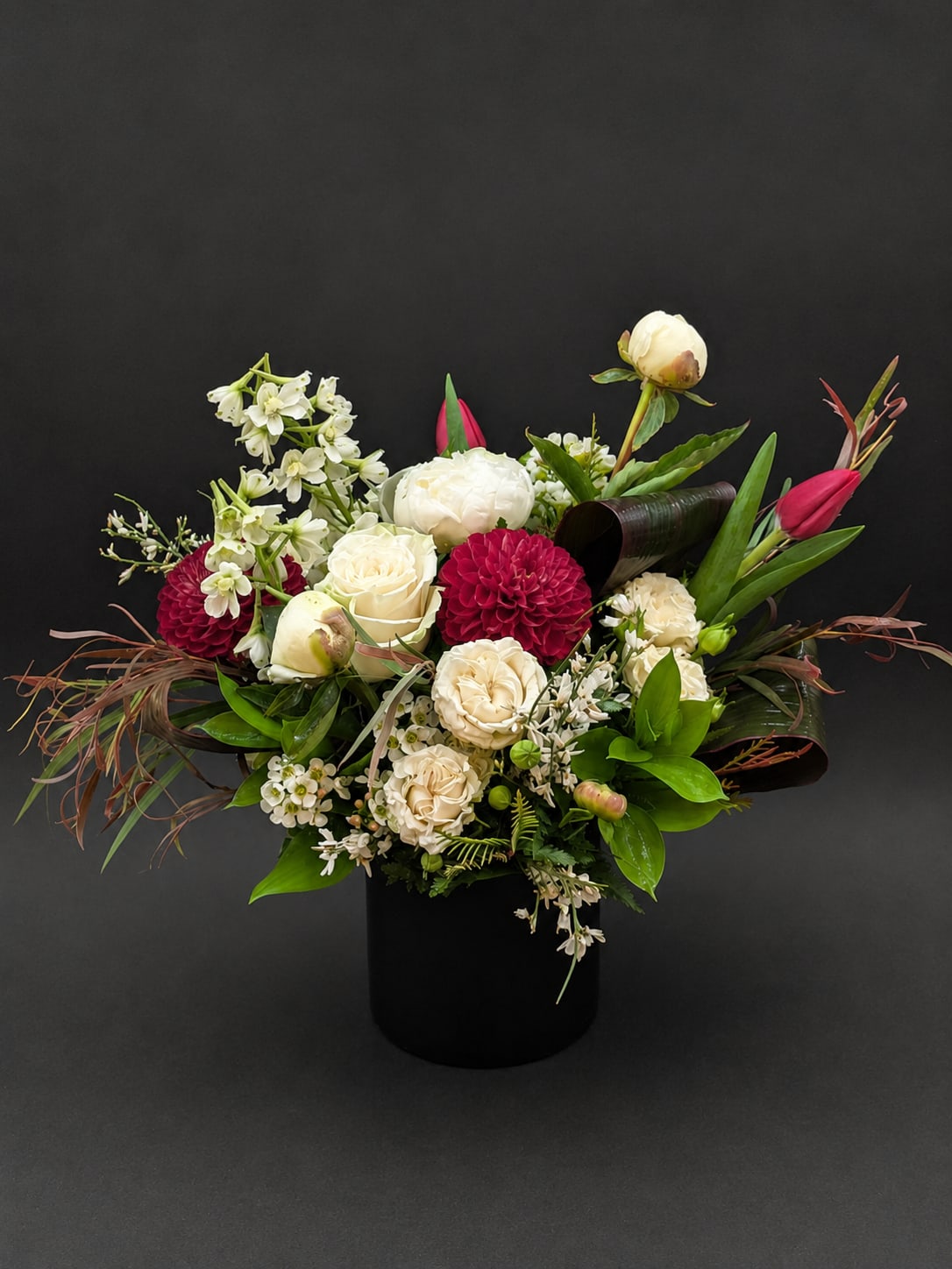 Mixed bouquet of white and deep pink flowers in a black vase