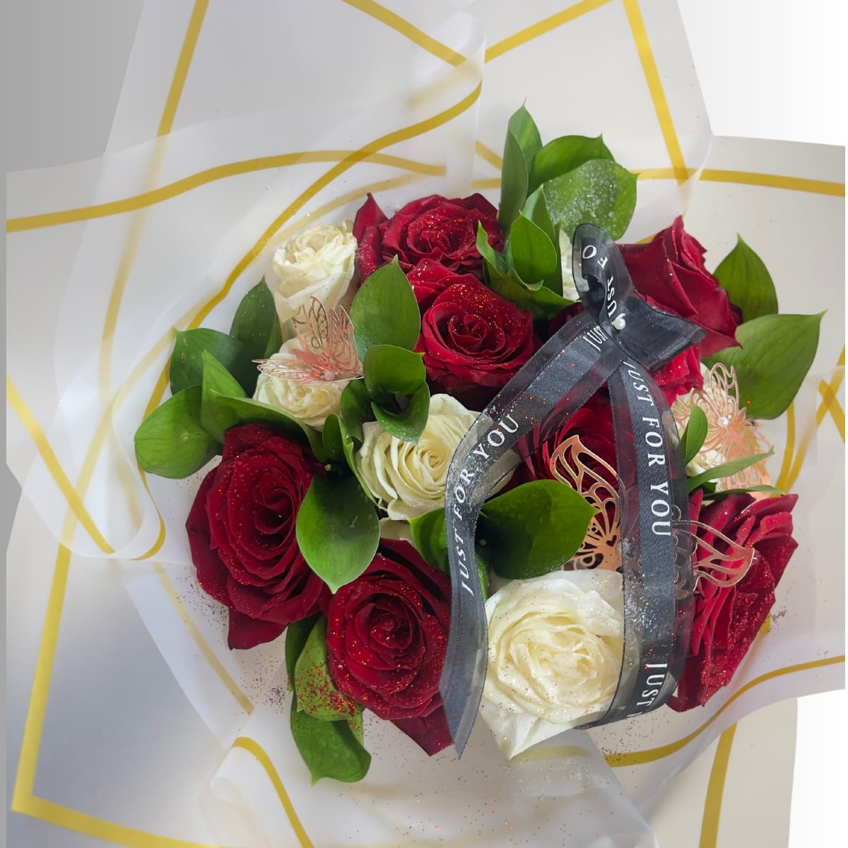 Bouquet of red and white roses wrapped in white paper with a black ribbon