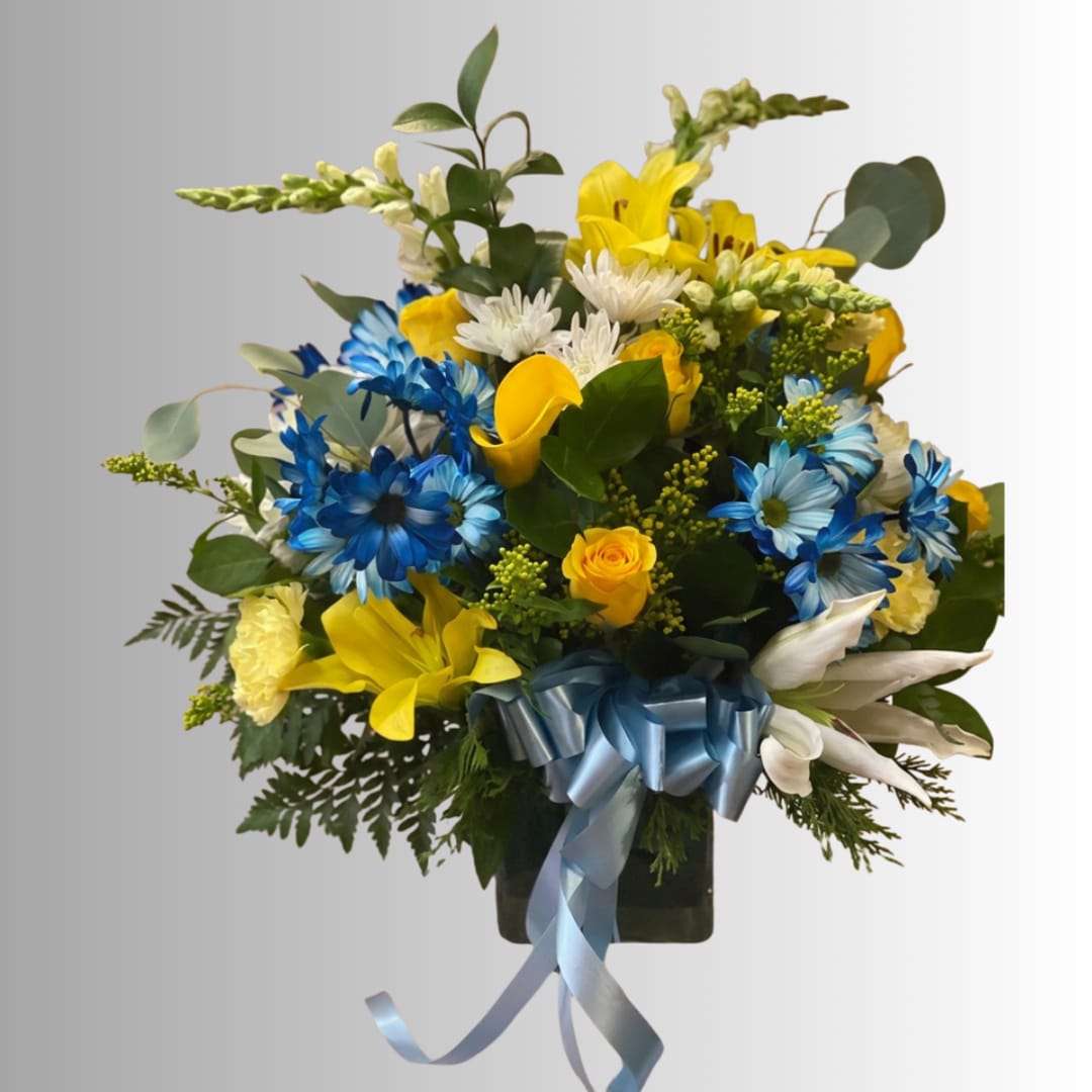 Bouquet of yellow, blue, and white flowers in a dark vase with a blue ribbon