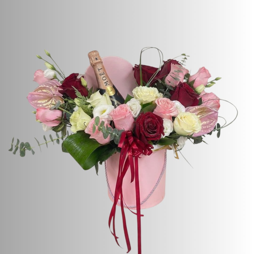 Pink and red rose arrangement in a pink hatbox with a champagne bottle