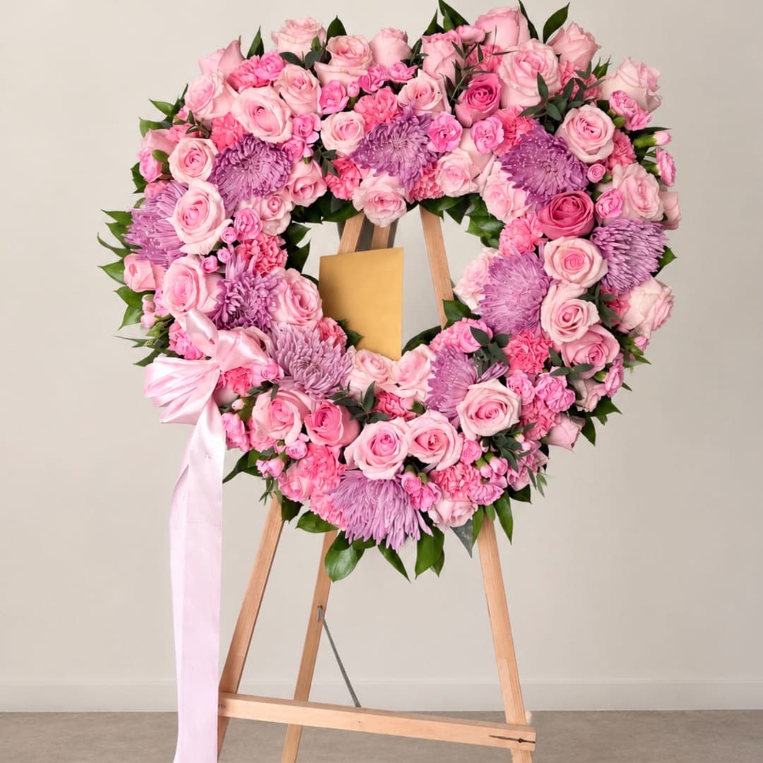 Pink and lavender floral heart wreath on a wooden easel with a ribbon bow.