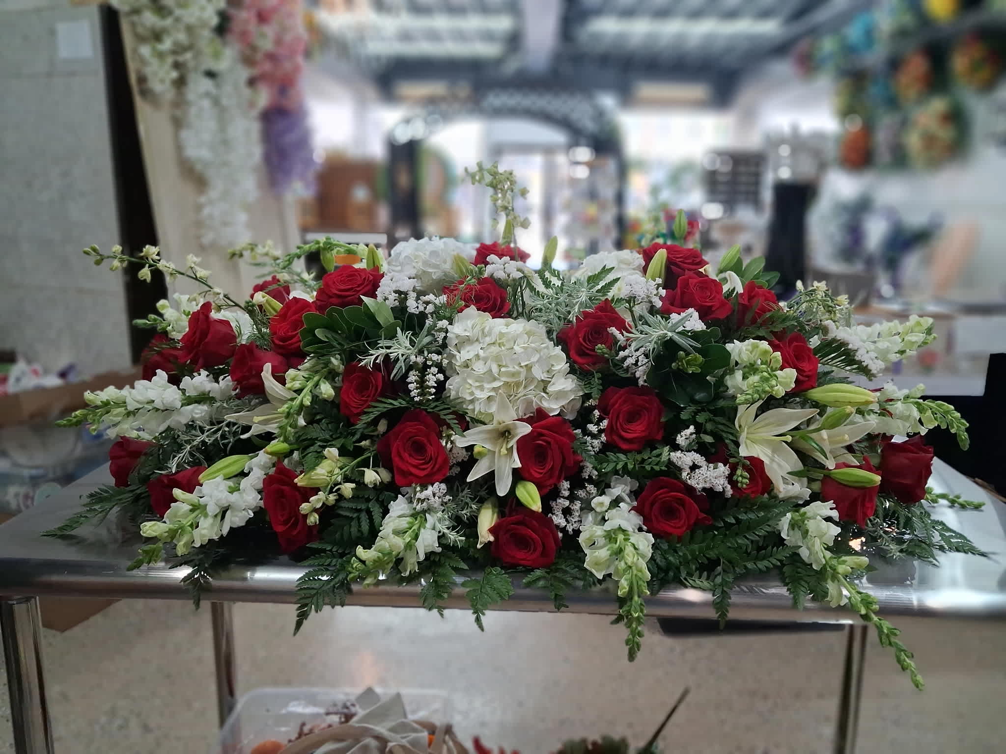 Low floral arrangement of red roses, white lilies, and white hydrangeas