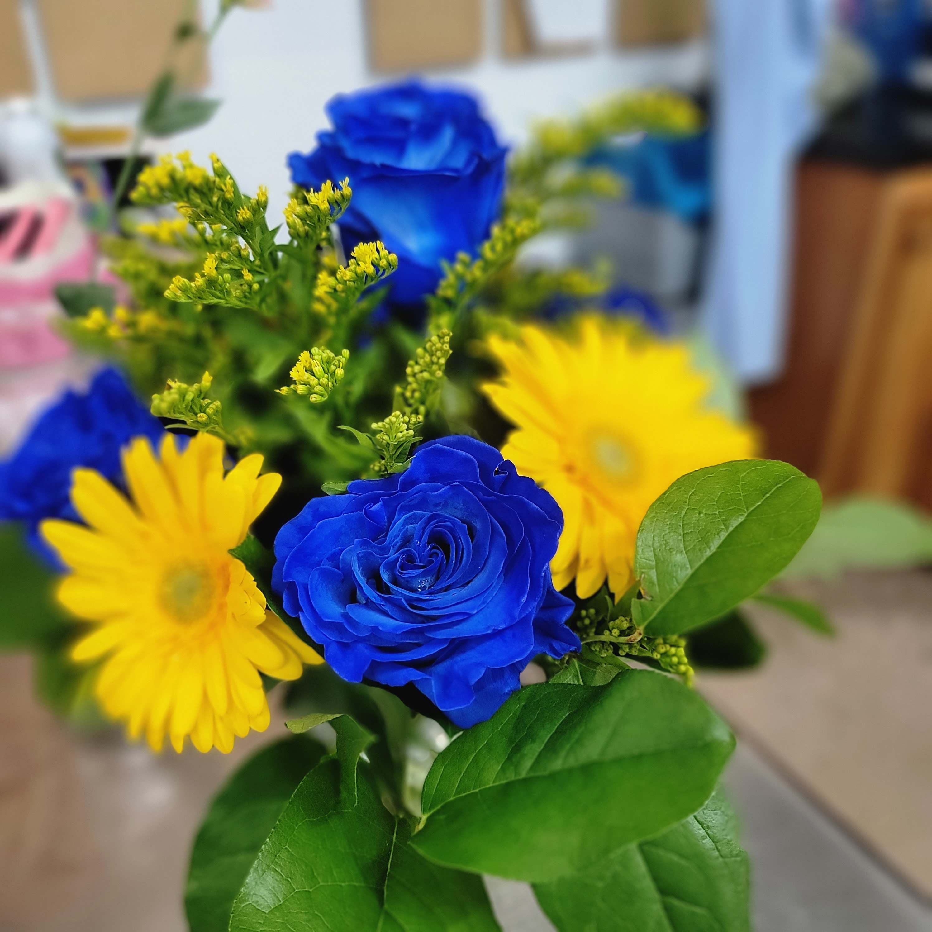 Bouquet of blue roses and yellow daisies with green foliage