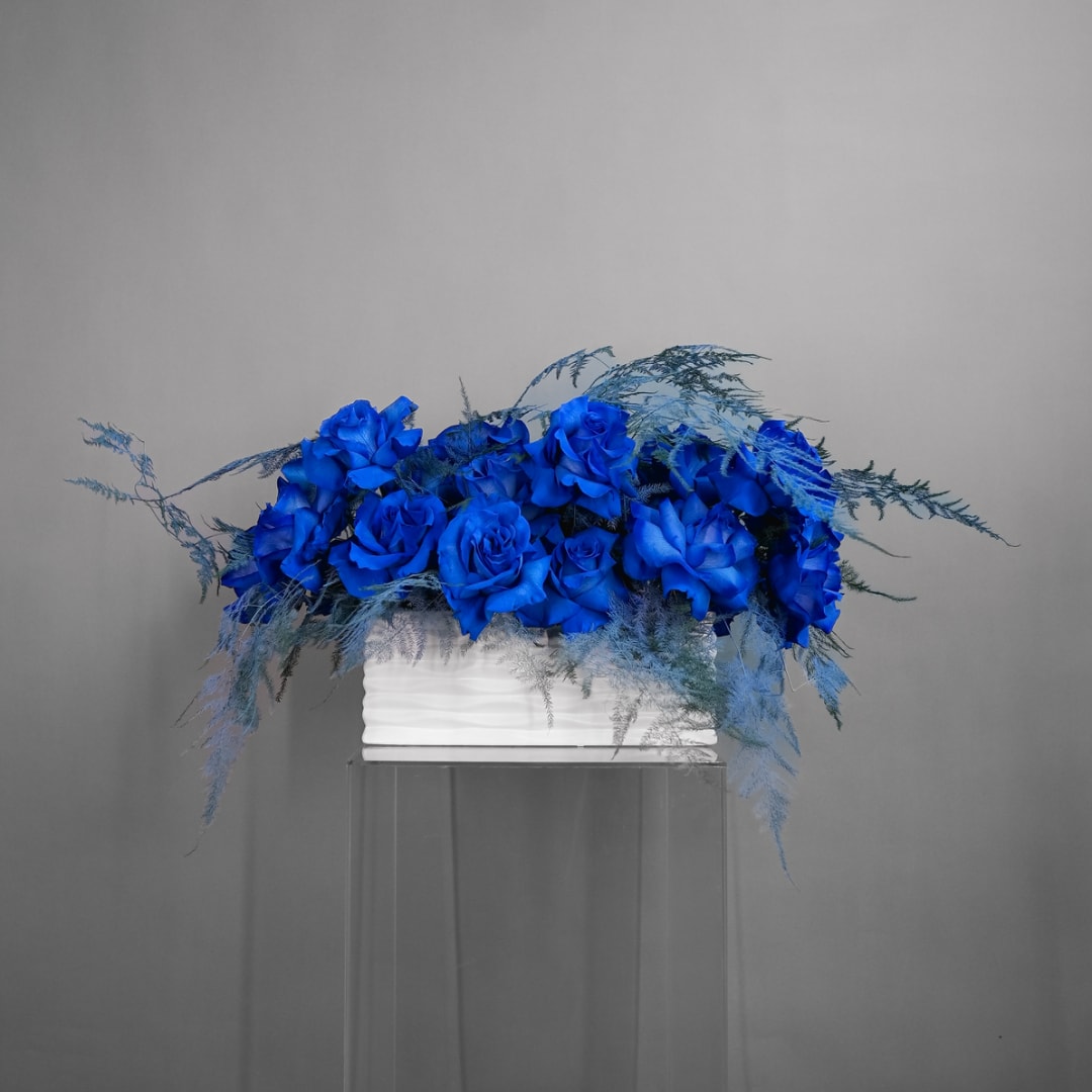 Blue rose arrangement in a white rectangular container