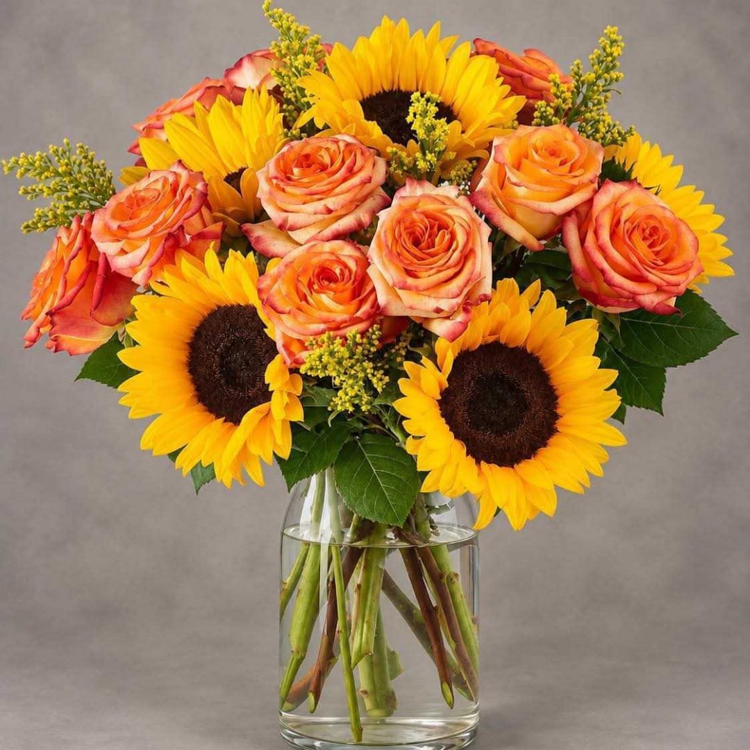 Bouquet of orange roses and yellow sunflowers in a clear glass vase