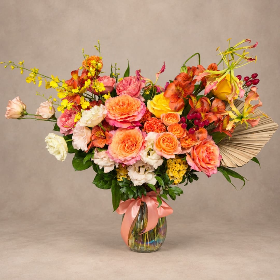 Colorful bouquet of roses, carnations, and orchids in a glass vase