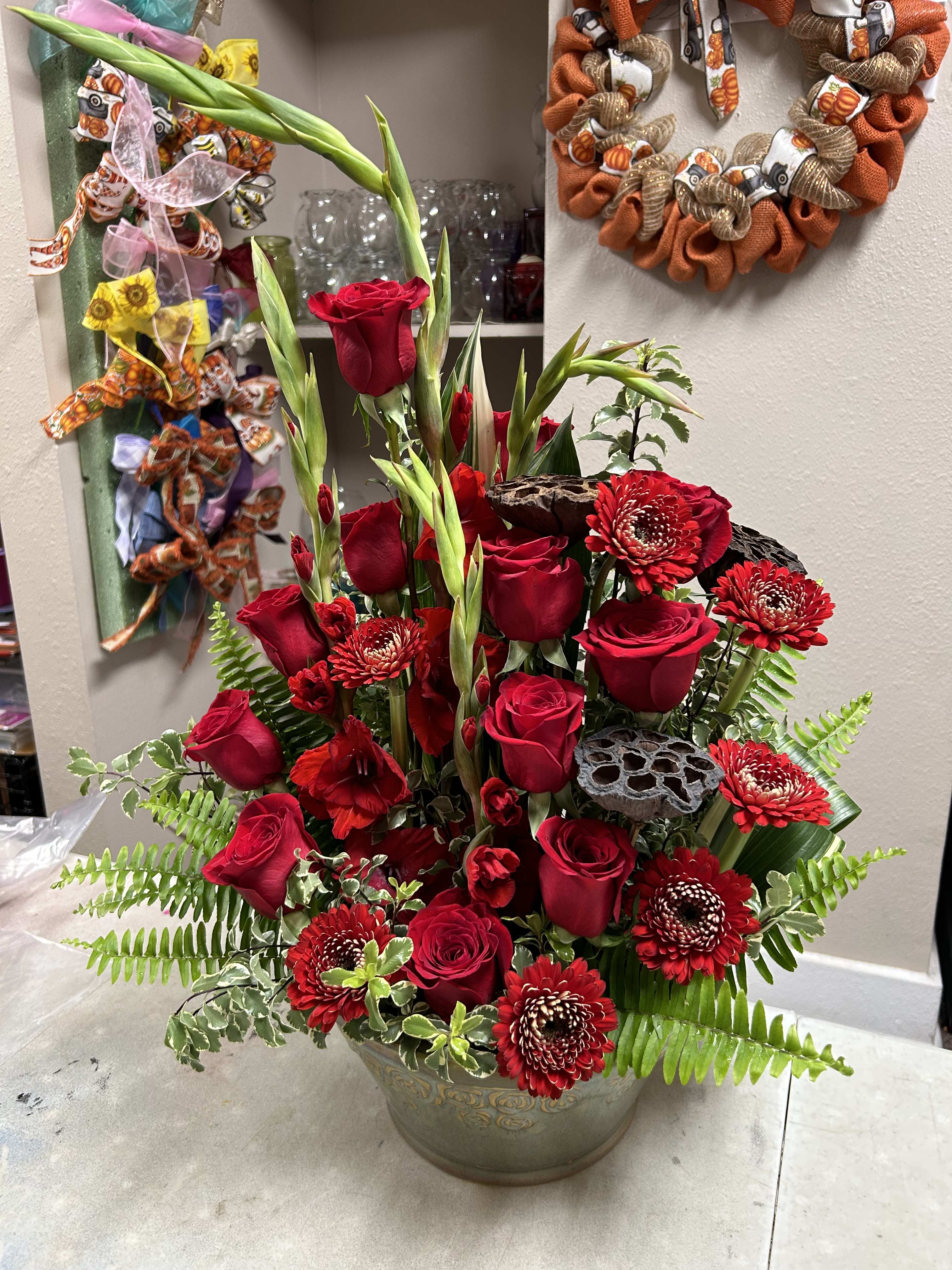 Tall arrangement of red roses and red chrysanthemums in a vase