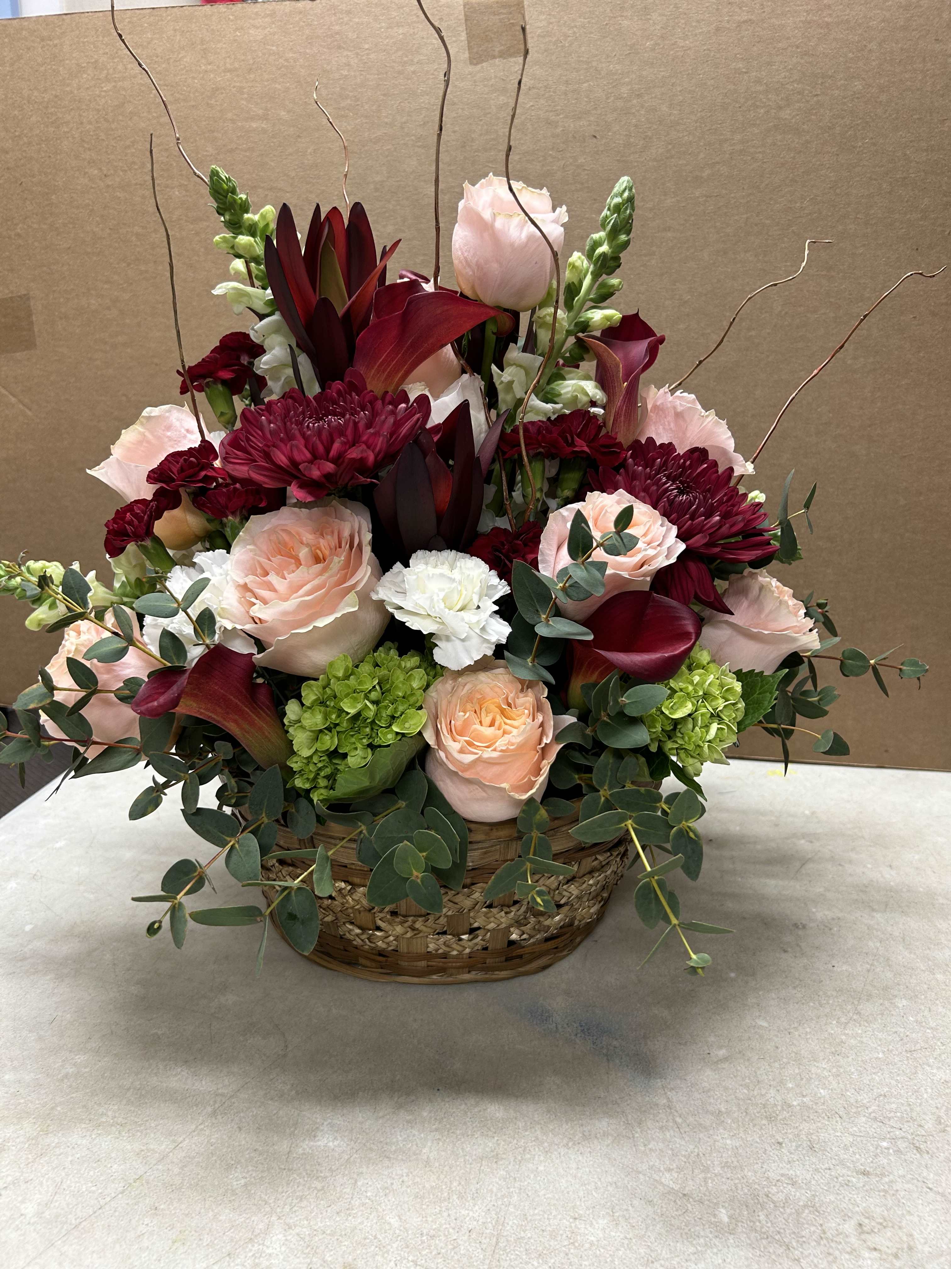Basket arrangement of pink and burgundy flowers with eucalyptus