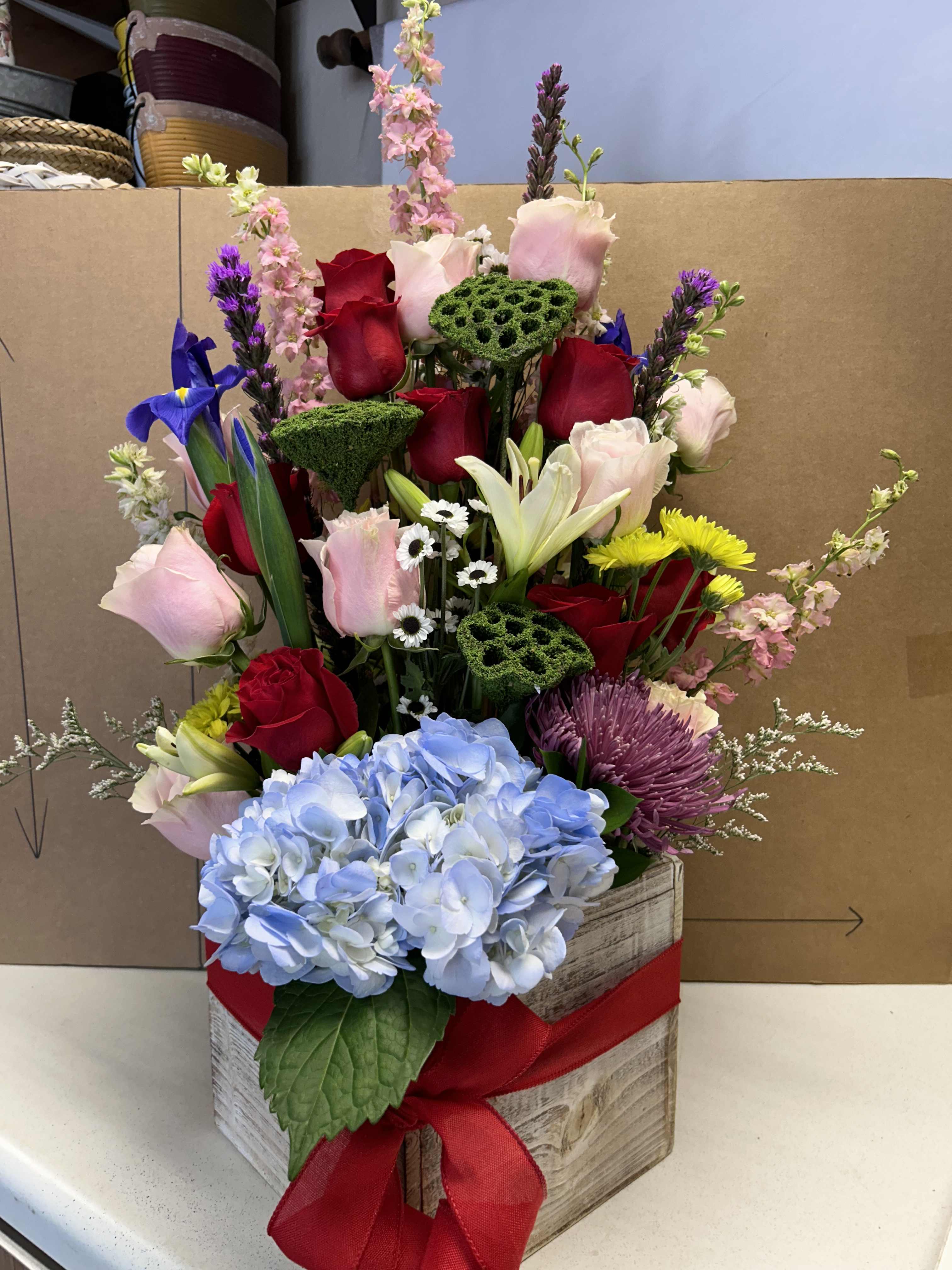 Mixed bouquet in a wooden box with roses, hydrangea, and lilies