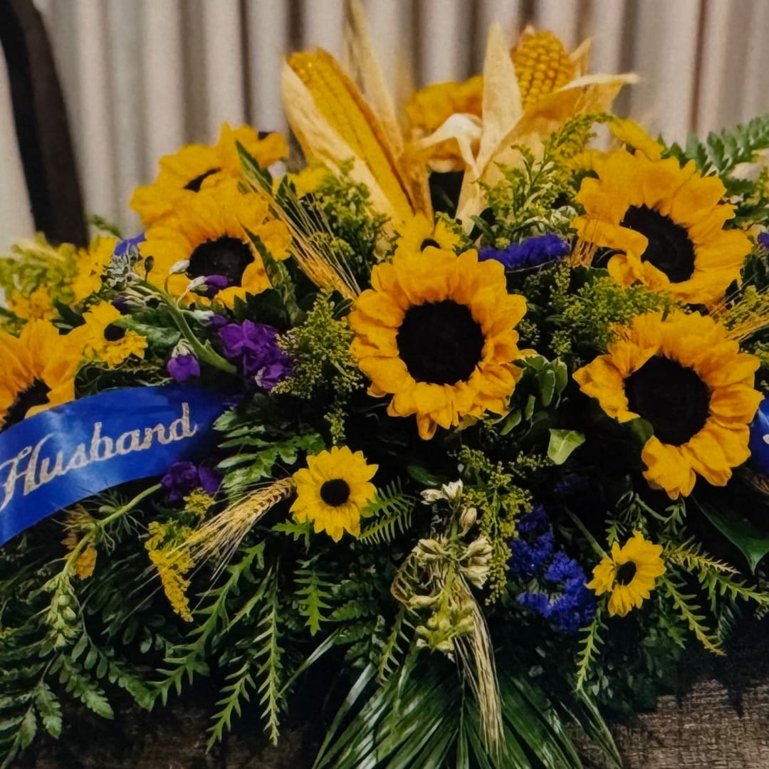 Large sunflower arrangement with a blue ribbon and mixed greenery