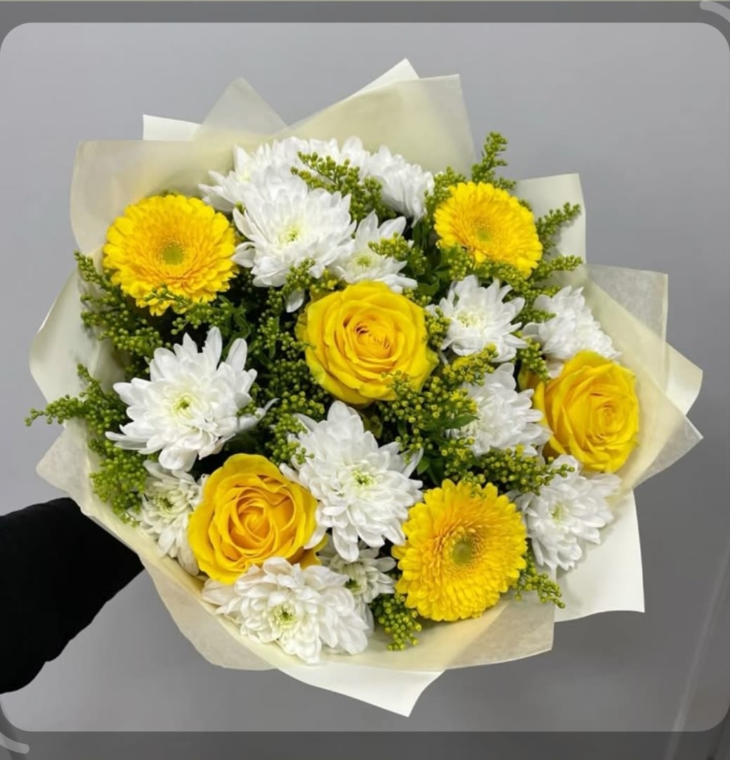 Bouquet of yellow roses and white daisies wrapped in pale paper