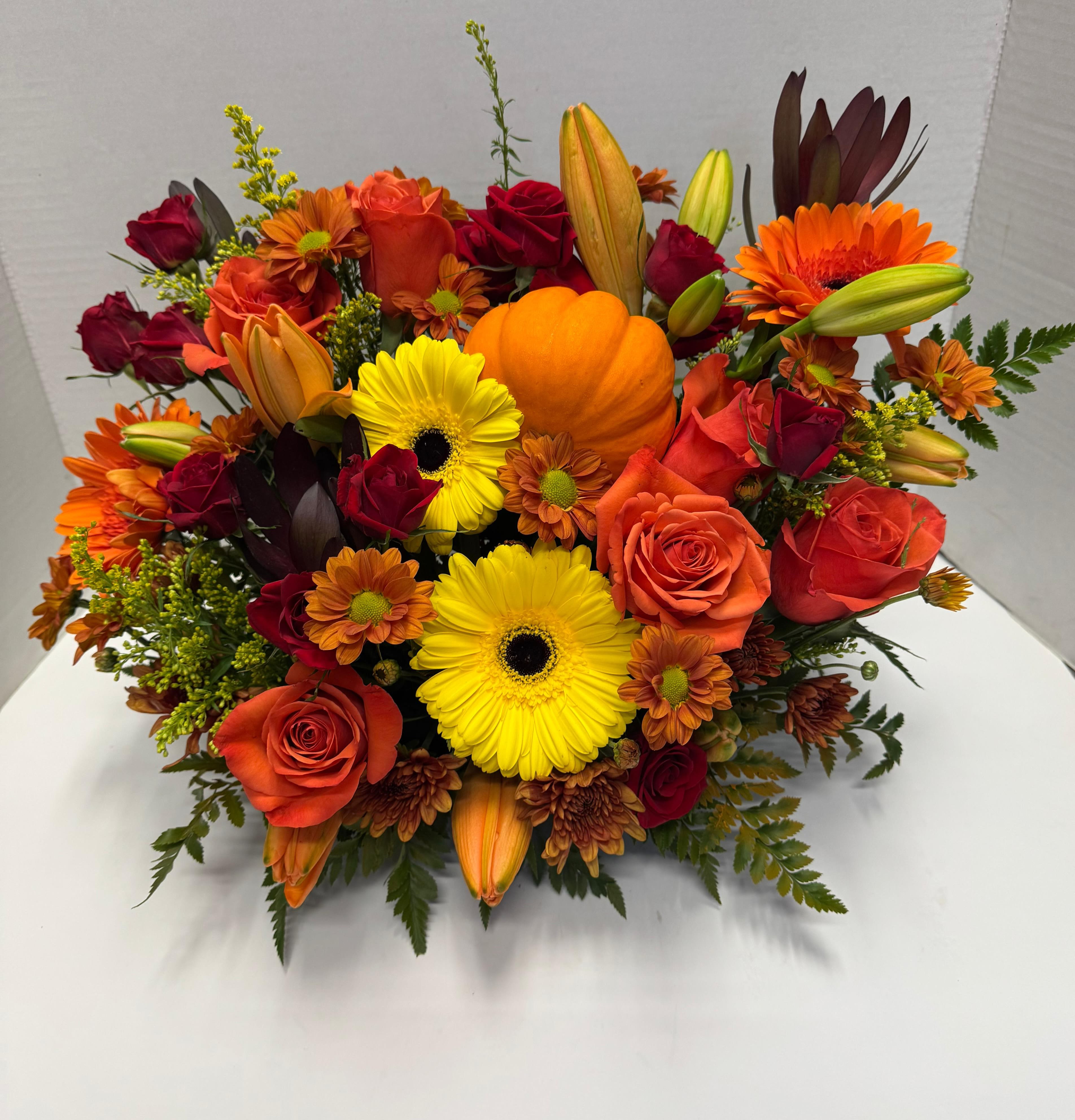 Bright Fall Arrangement  - Celebrate the beauty of autumn with the Bright Fall Arrangement, stunning arrangement of rich oranges, warm yellows, and deep reds. Featuring bold orange roses, and seasonal fall blooms, this bouquet captures the essence of the season’s colors while offering a touch of elegance and vibrancy. 