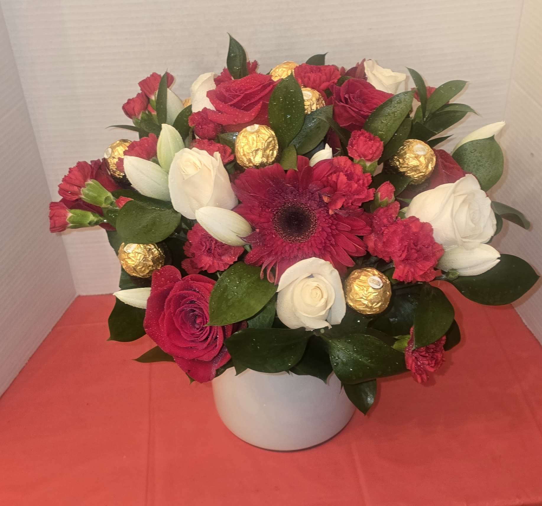Magic Arrangement - "This designer floral arrangement captures the essence of an enchanted garden.  With a base of lush, asymmetrical foliage, the striking white and pink tulips with their firm petals add dimensional depth. The chocolates provide an extra touch, transforming any space into a haven of serenity and contemporary luxury."