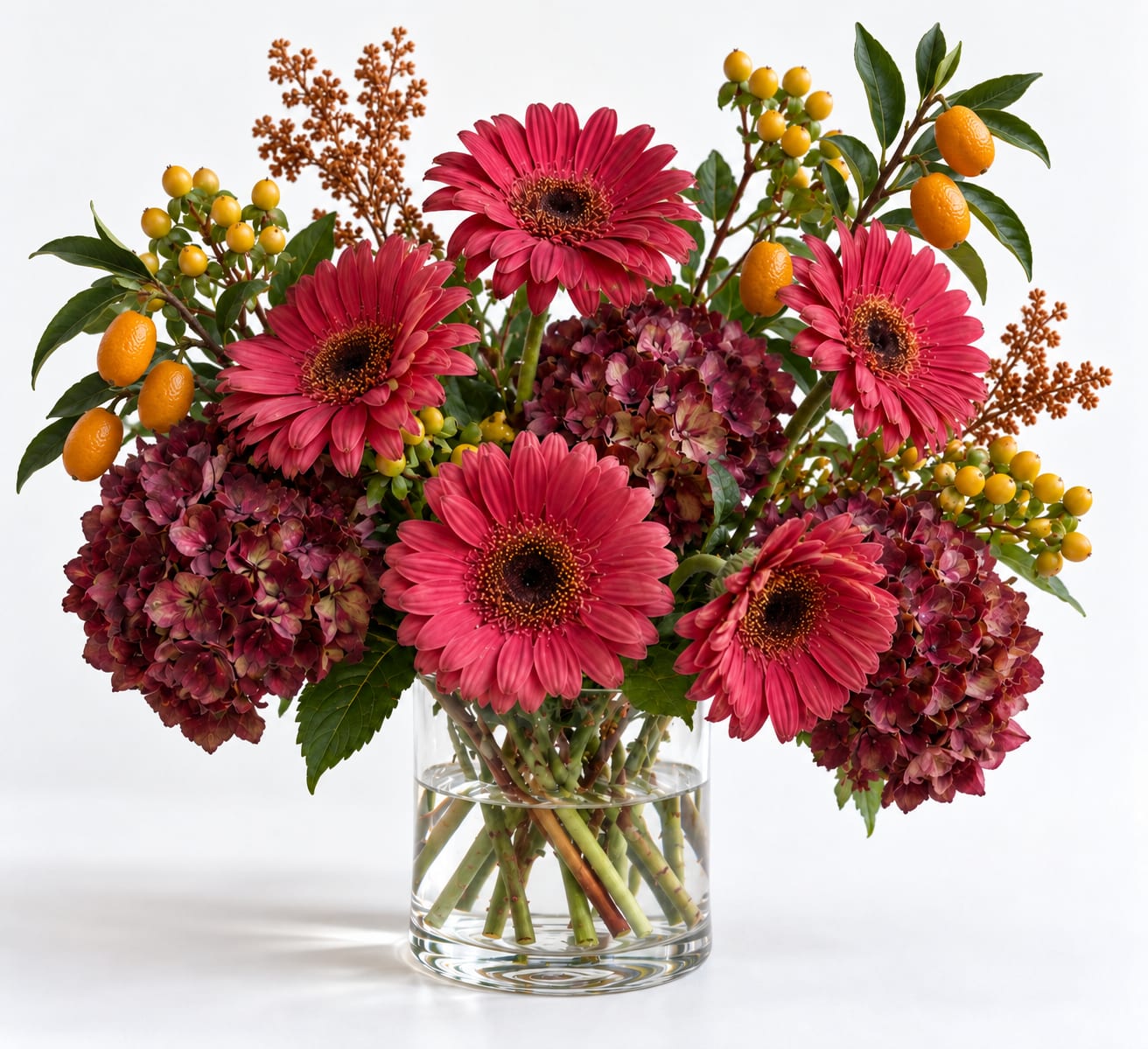 Pink gerbera daisies and burgundy hydrangeas in a clear glass vase