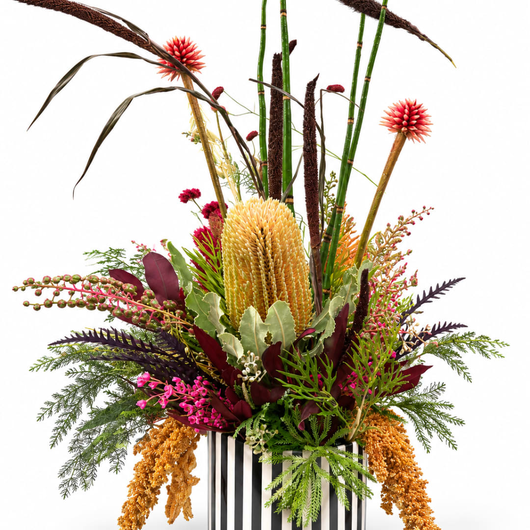 Tall tropical arrangement with spiky blooms in a striped container