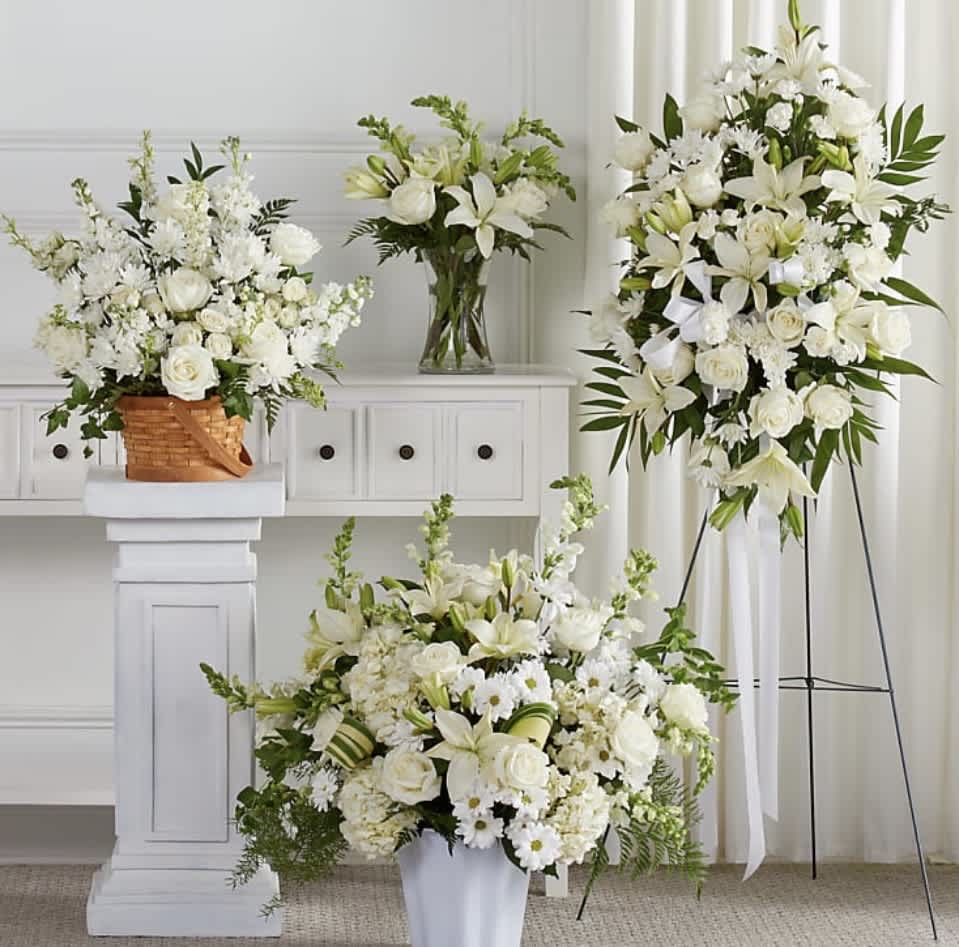 White floral arrangements with lilies and roses in baskets, vases, and a standing spray