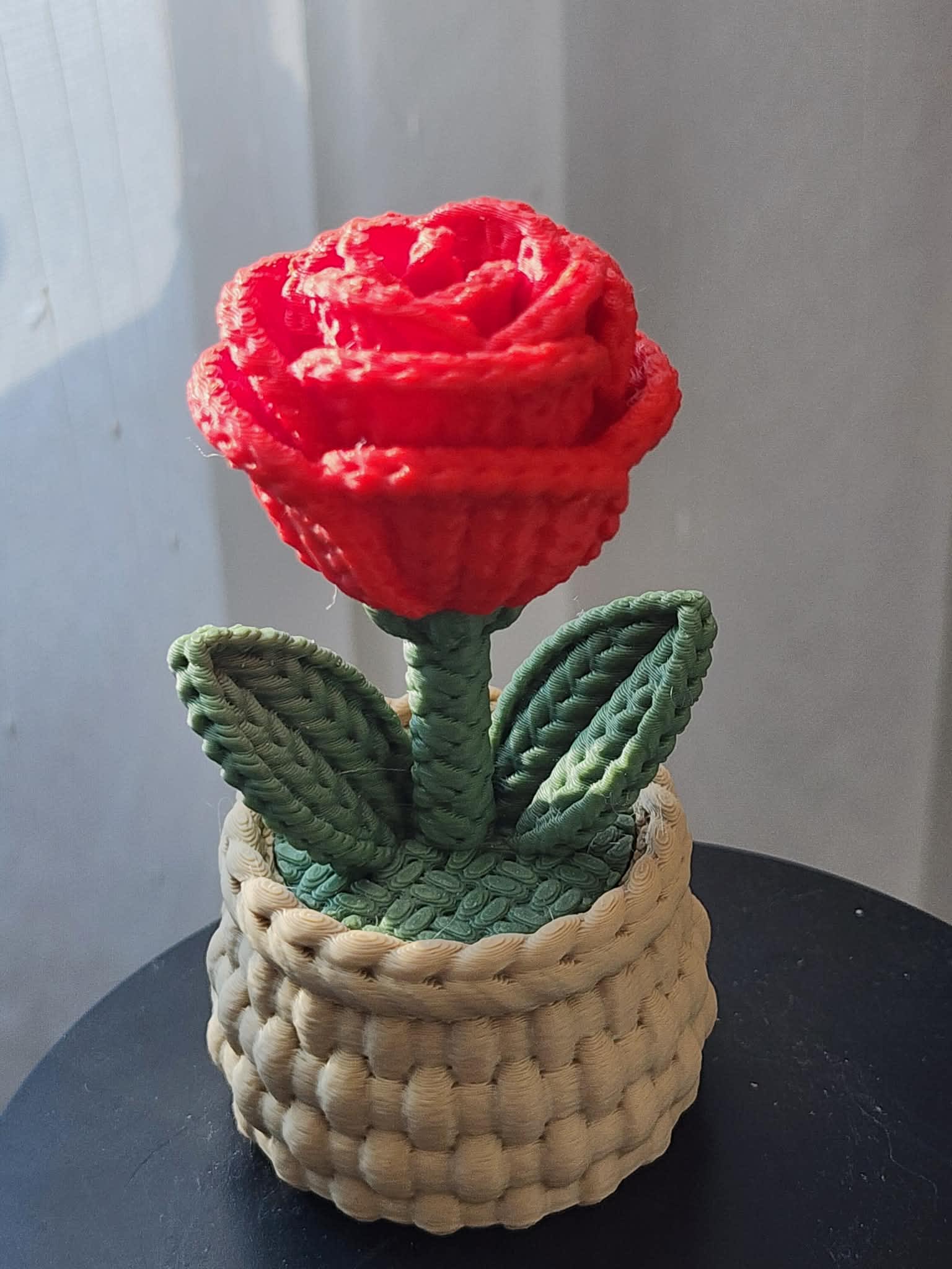 Red rose-shaped decorative piece in a woven basket planter