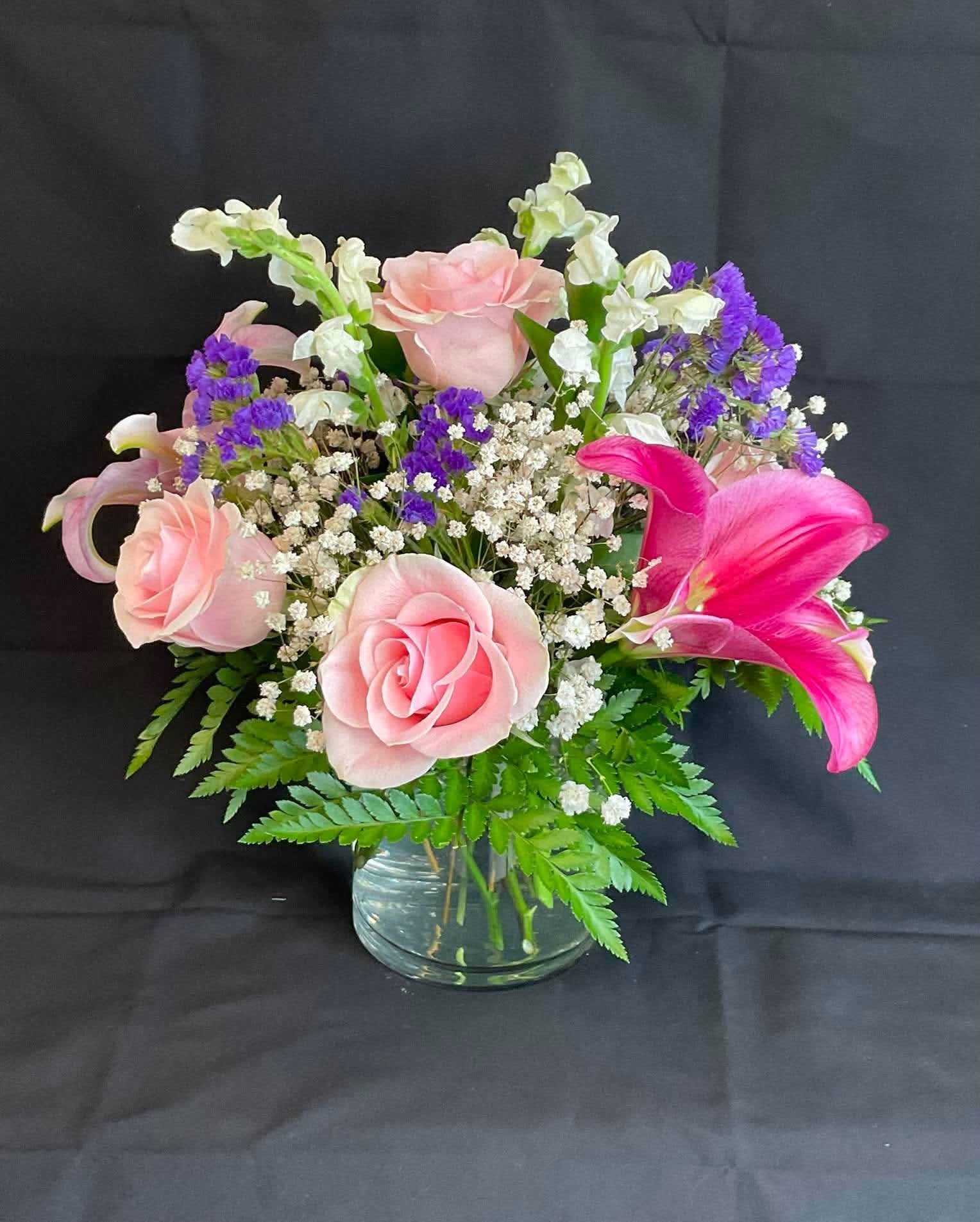 Pink roses and a bright pink lily in a glass vase