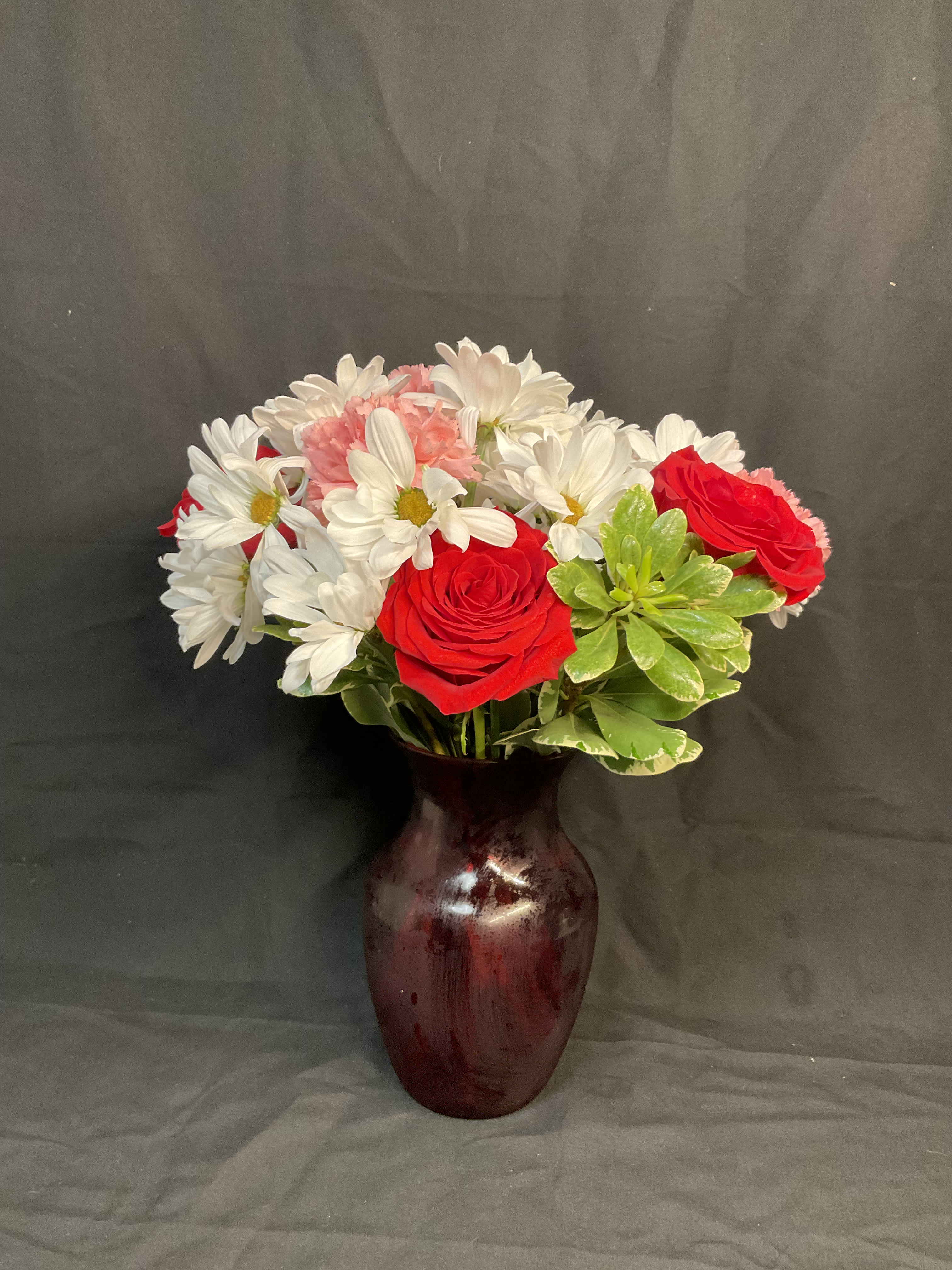 Red roses and white daisies in a burgundy vase