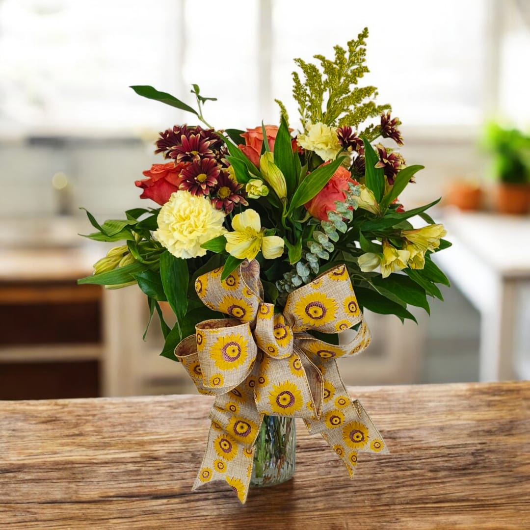 Mixed bouquet in a glass vase with a large patterned ribbon