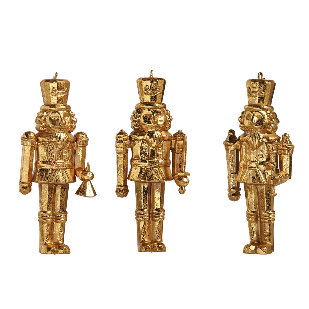 Three gold nutcracker ornaments on a white background