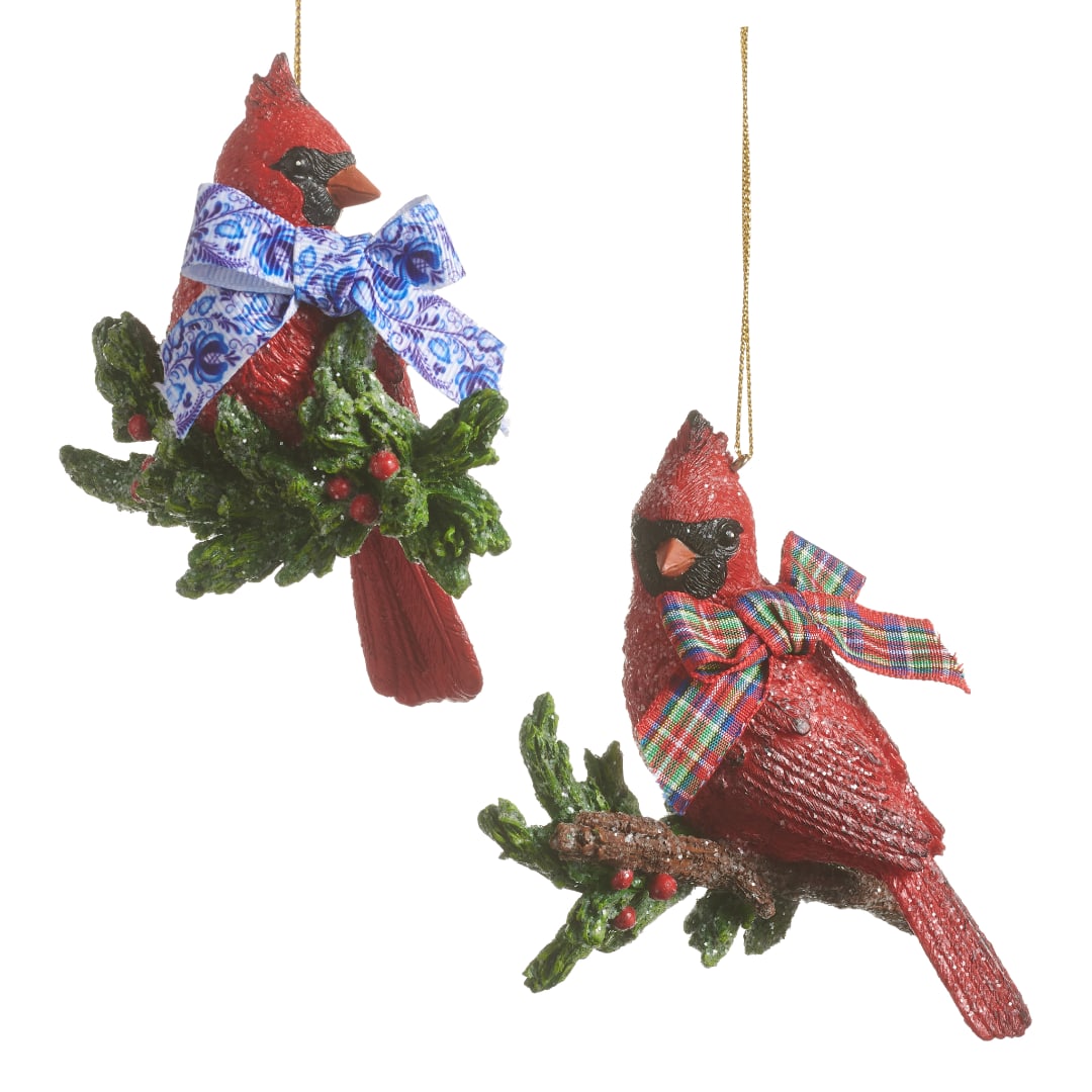 Two cardinal bird ornaments with bows hang on a white background