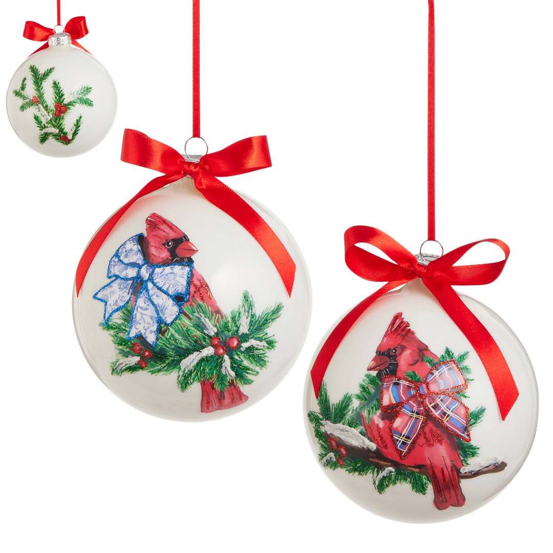 Three white Christmas ornaments with red bows and cardinal designs