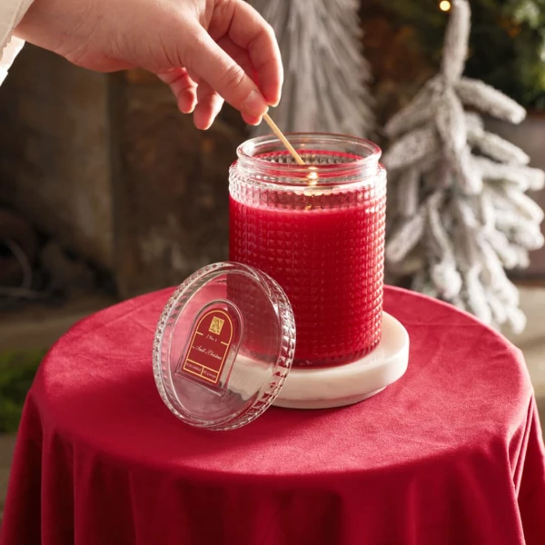 Red candle in a textured glass jar with a lid on a table
