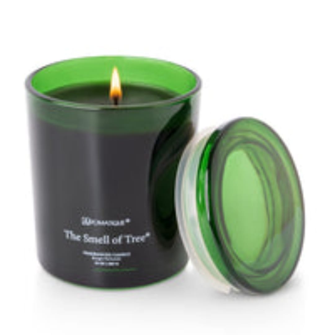 Green glass candle jar with a lit wick and matching lid