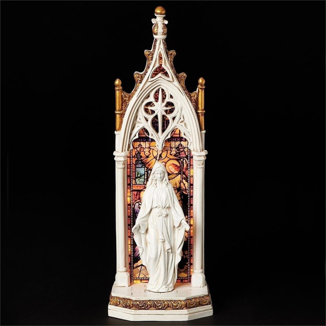 White religious statue in a Gothic-style arch with stained-glass backdrop