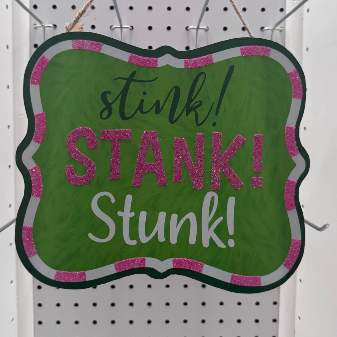 Green hanging sign with pink glitter trim reading "stink! STANK! Stunk!"