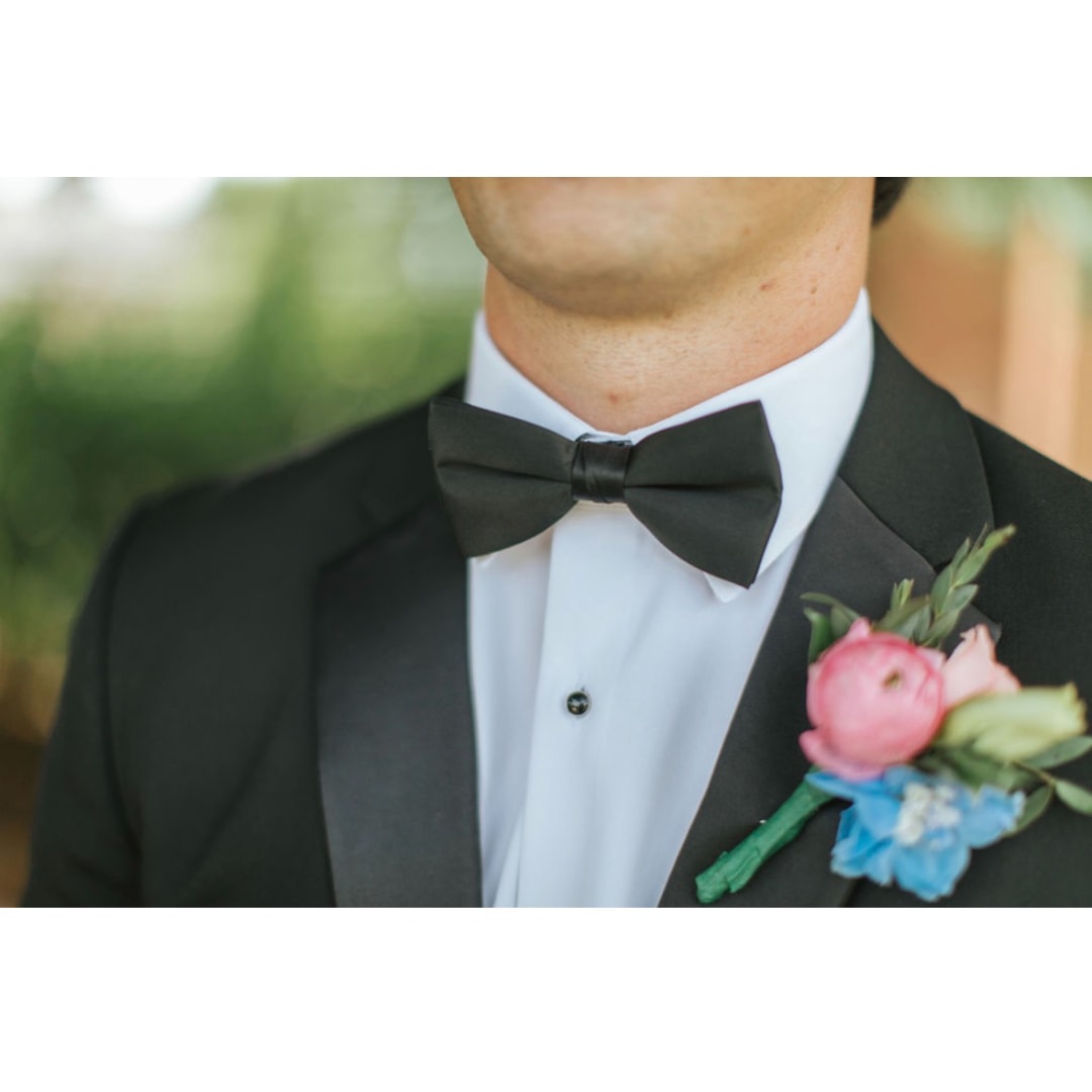 Groom in a tuxedo wearing a pink and blue boutonniere