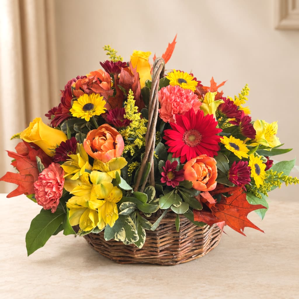 Basket arrangement of mixed fall flowers in yellow, orange, red, and pink