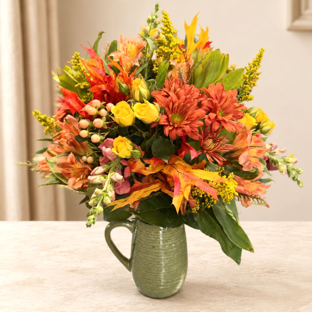 Autumn bouquet of orange and yellow flowers in a green ceramic pitcher