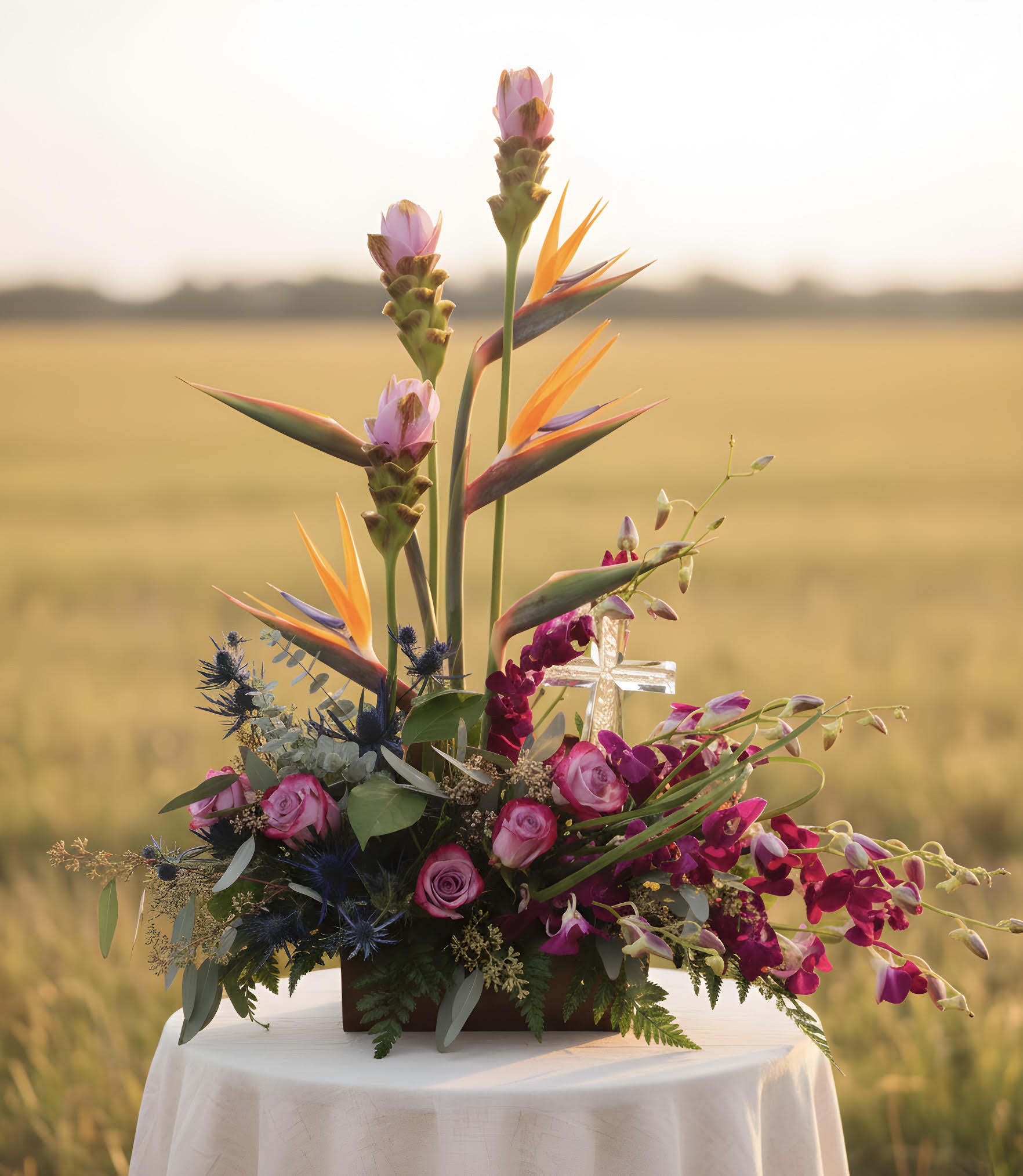 Tropical floral arrangement with pink roses and bird-of-paradise blooms in a low container