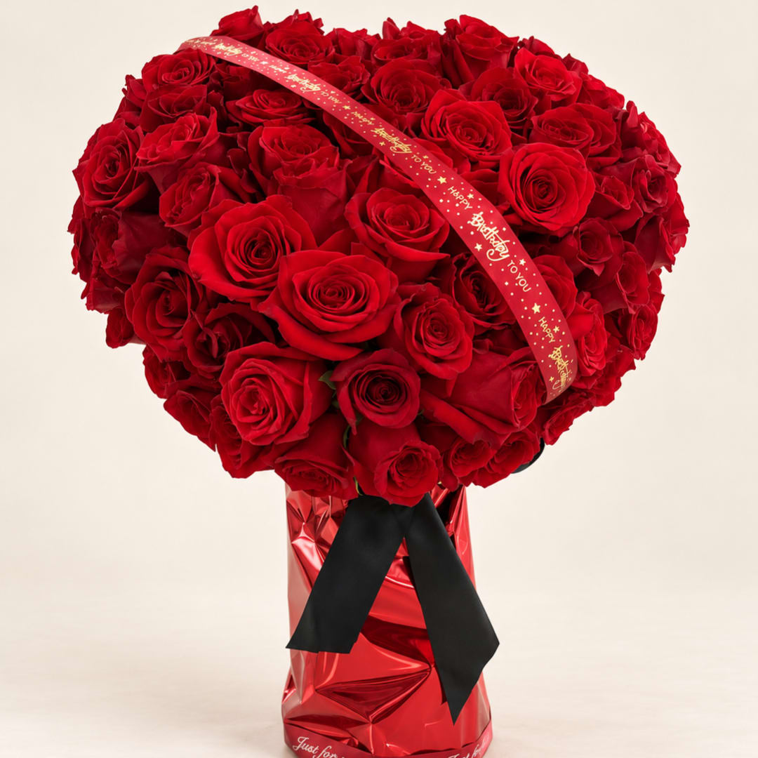 Large bouquet of red roses with a decorative ribbon in a red wrapped vase